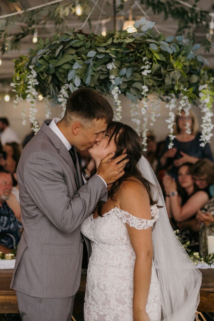 A bride and groom sharing a kiss during their wedding reception at The Greenhouse At Bittersweet.